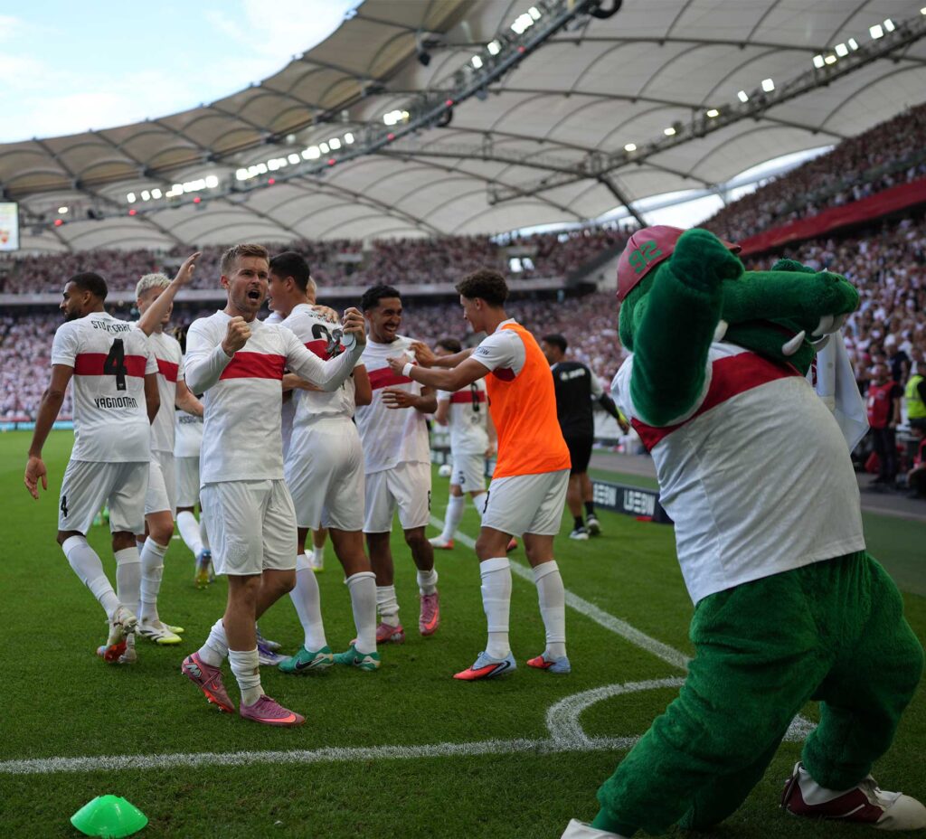 Jubelnde Spieler des VfB Stuttgart im Stadion, rechts das Maskottchen